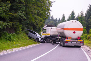 A truck and car sit on a forested road after a serious crash, leaving the car driver to wonder whether they can sue the trucking company after an accident.