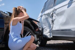 A woman checking the damage of a car accident, wondering how to file a lawsuit in Washington State.