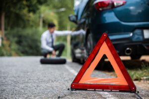 A hazard sign behind a crashed car. What are the most common types of car accident injuries?